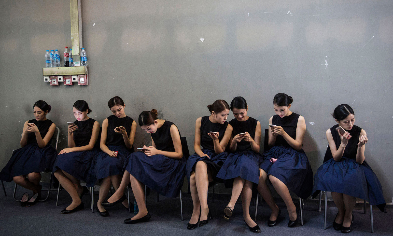 Exhibit hostesses using smartphones during the China (Guangzhou) International Automobile Exhibition