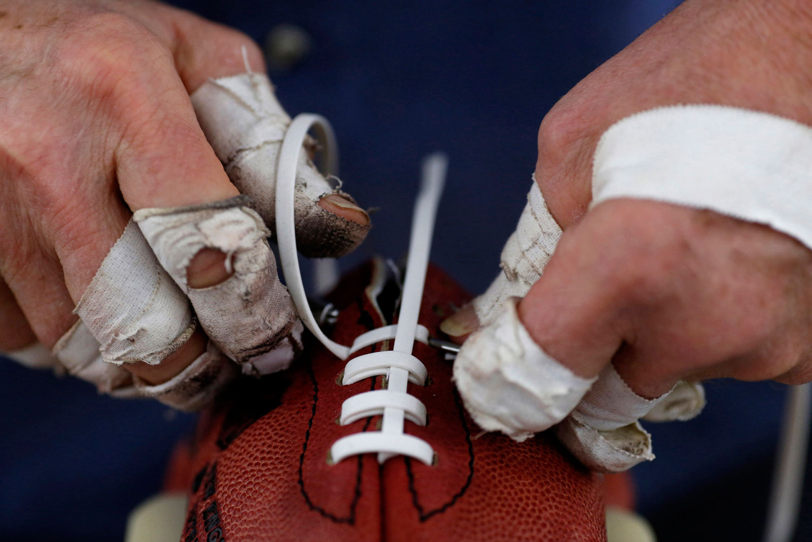 A worker installs laces on a football at the Wilson Sporting Goods factory in Ada, Ohio