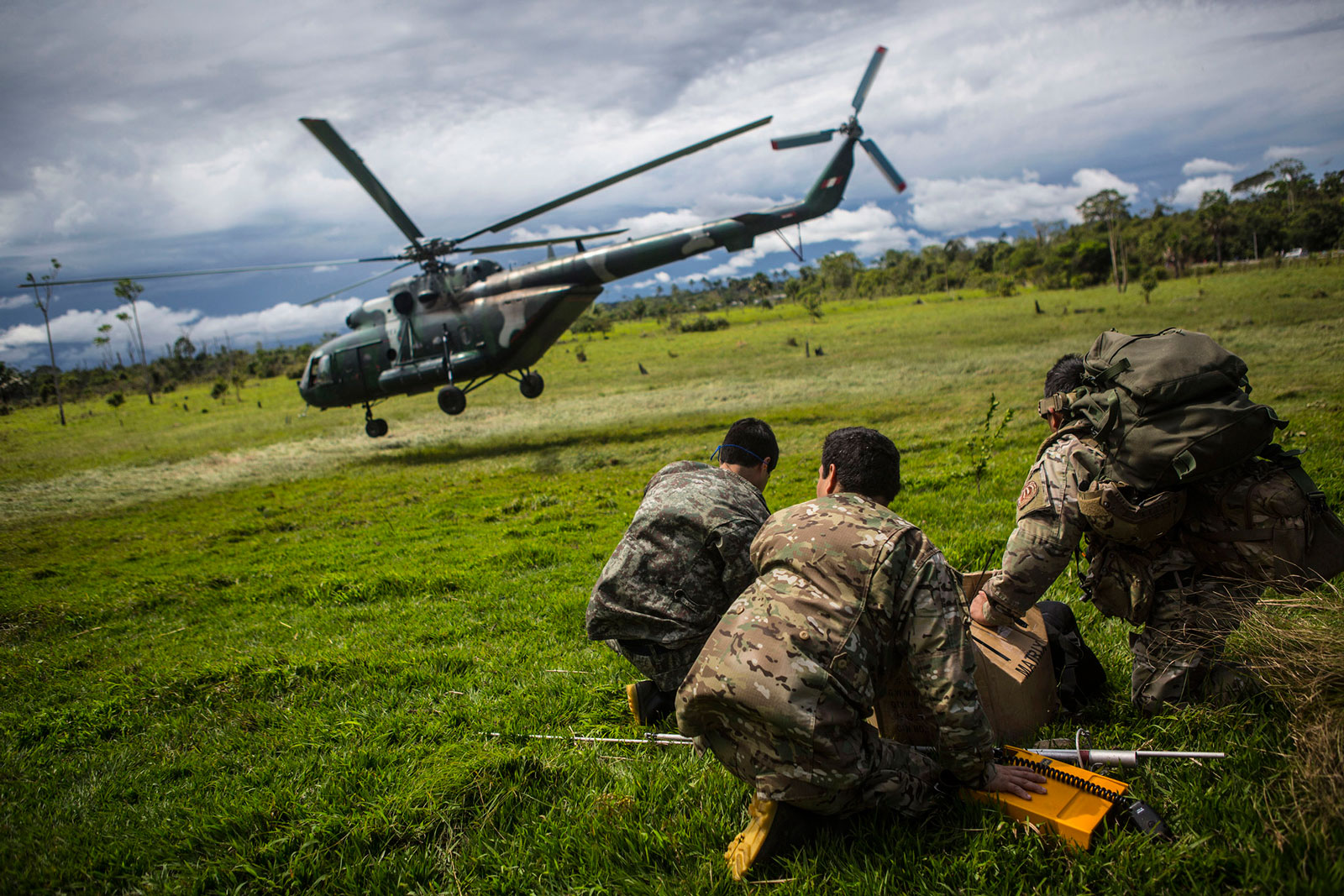 Police officers look on as a helicopter loaded with supplies and crew flies out to raid an illegal gold mining camp inside the Amazonian National Reserve buffering zone of Tambopata in Puerto Maldonado, Peru