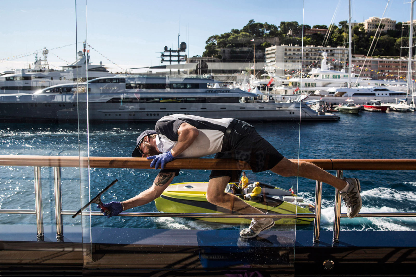 A crew member cleans windows aboard superyacht Solandge, built by Germany’s Lürssen Werft and moored at the Monaco Yacht Show in Port Hercules, Monaco