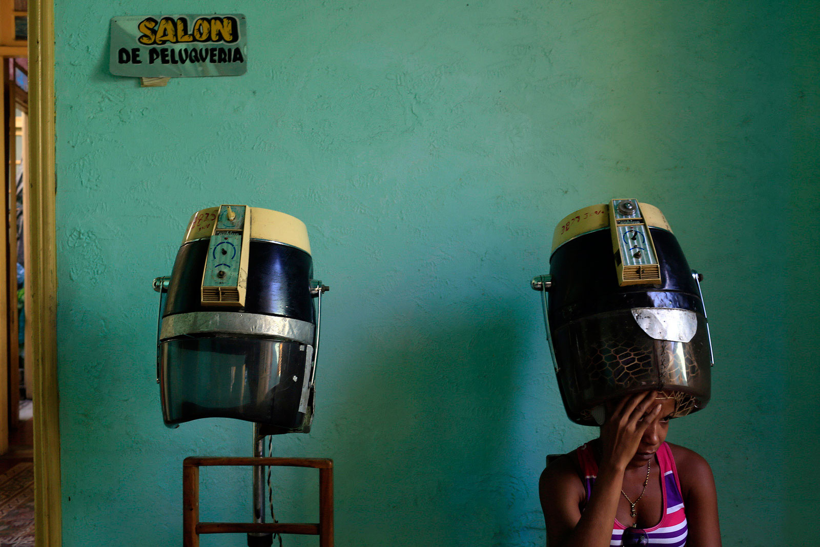 A woman gets her hair styled at a salon in Santiago de Cuba