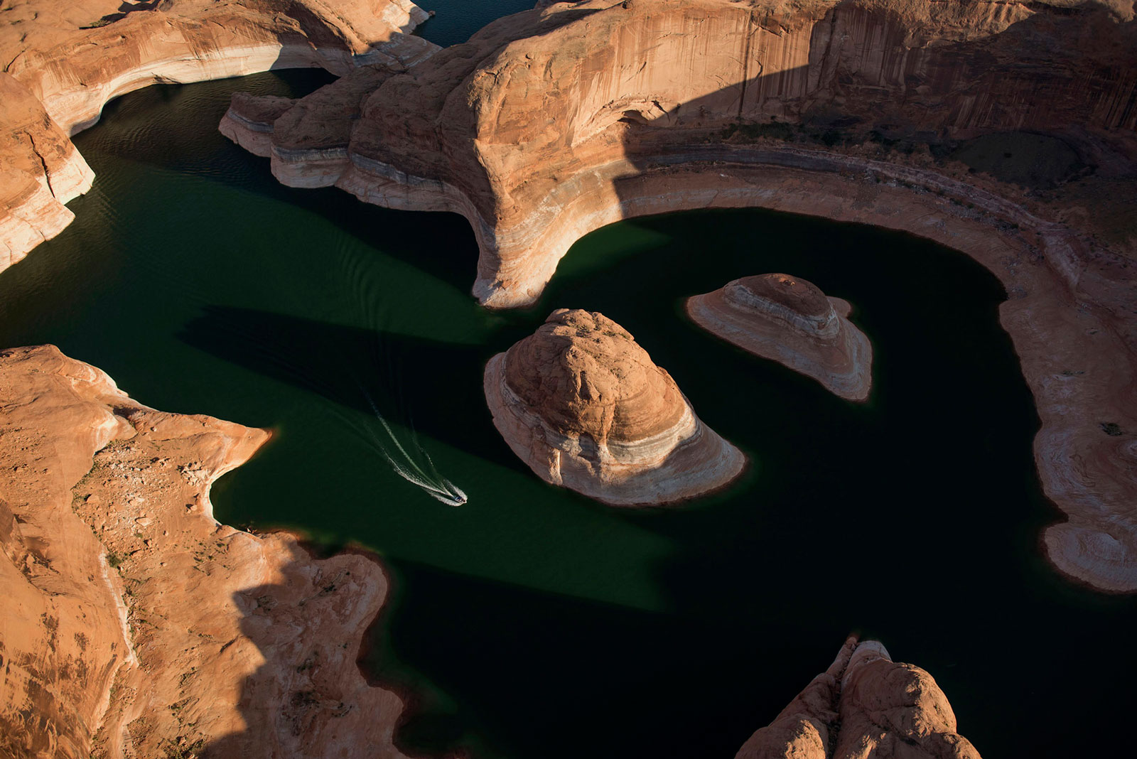 A boat moves along the shore of Lake Powell in Page, Ariz.
