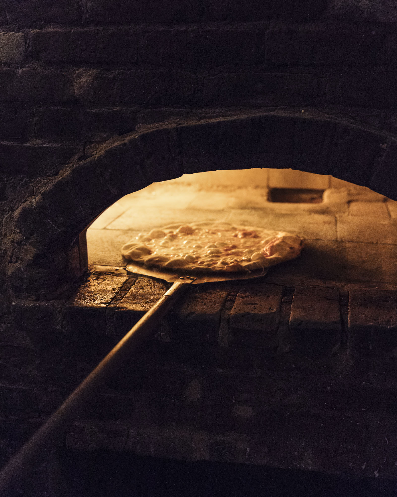 putting the pizza in a hot brick oven