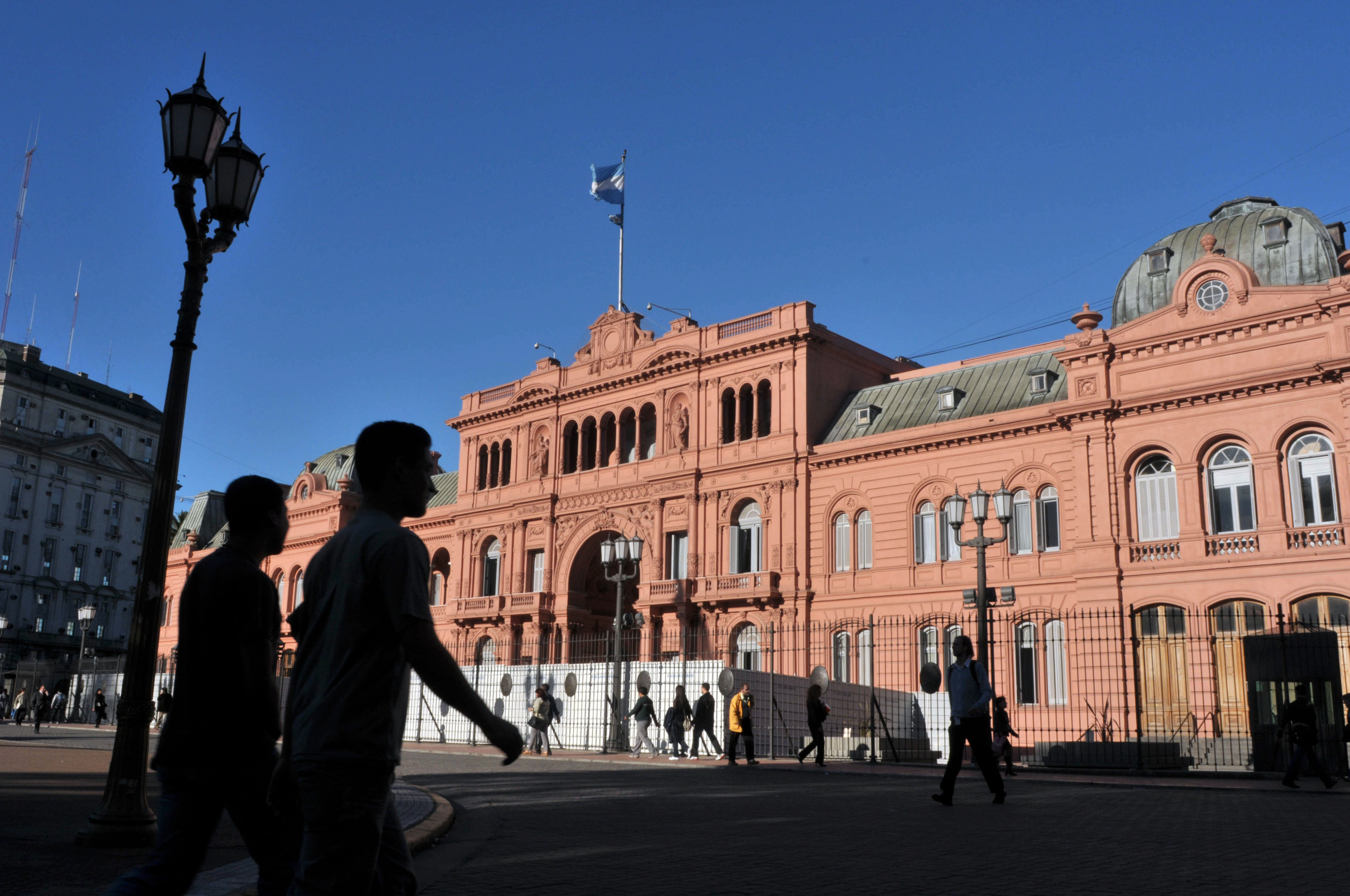 Pedestrians pass the Casa Rosada government palace in Buenos Aires, Argentina.
